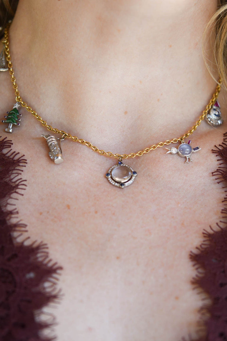 Antique Art Deco holiday-themed multi-gem platinum and 18K gold charm necklace with figural charms, circa 1920 on a model